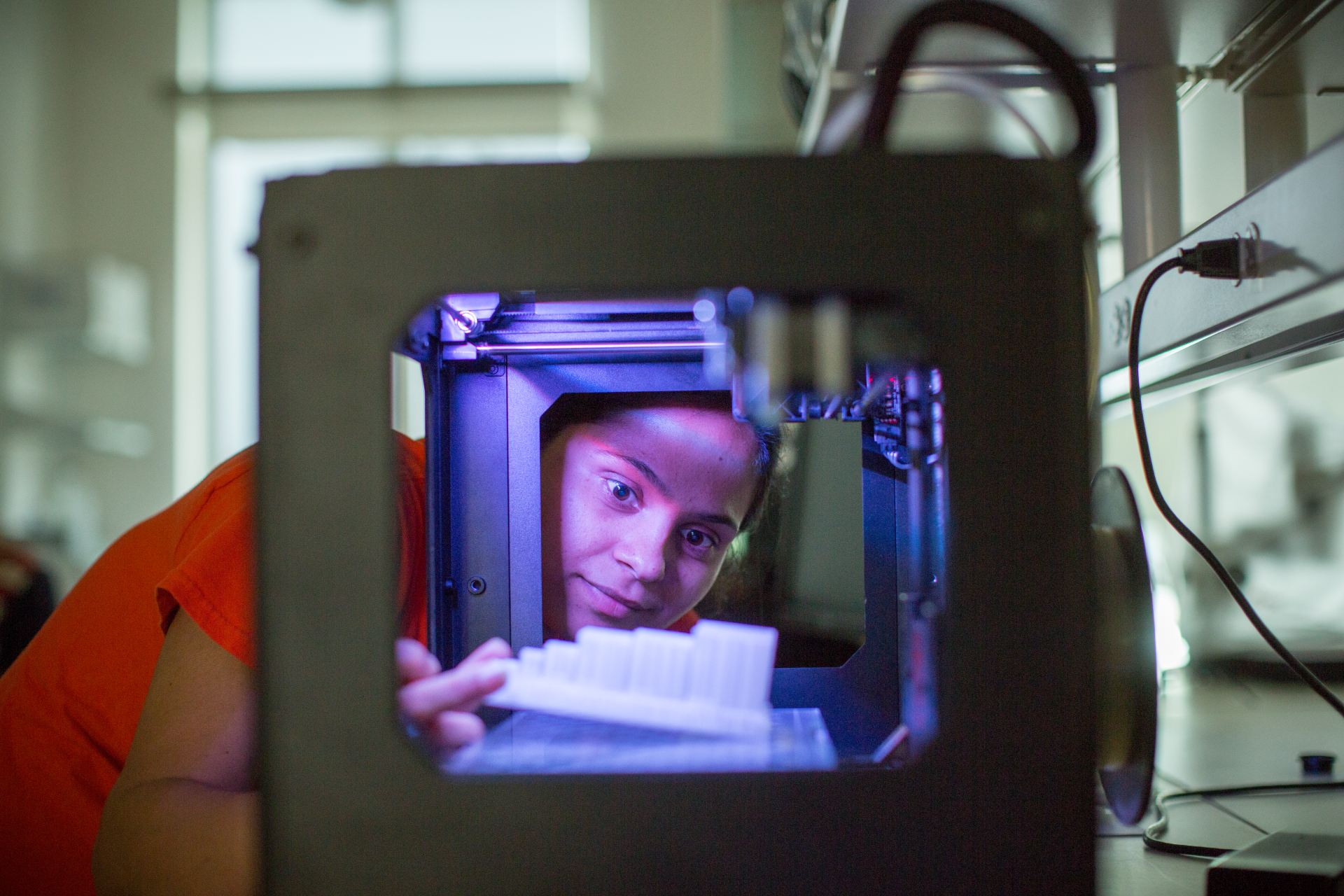Student observing material inside a 3D printer